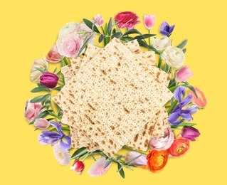 Tasty matzos and flowers on yellow background, flat lay. Passover (Pesach) celebration