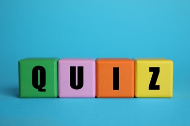 Colorful cubes with word Quiz on light blue background. Space for text