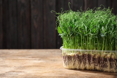 Photo of Fresh organic microgreen on wooden table. Space for text