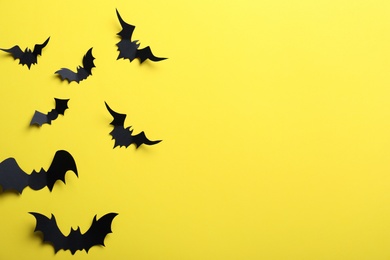 Paper bats on yellow background, flat lay with space for text. Halloween decor