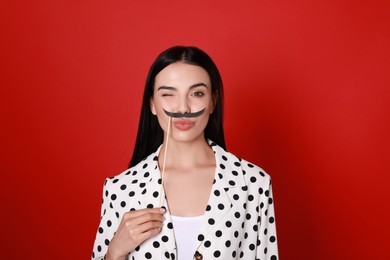 Photo of Funny woman with fake mustache on red background