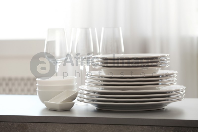 Photo of Set of clean dishware and wineglasses on table indoors