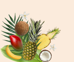 Tropical layout with fresh exotic fruits and green leaves on pale beige background, top view
