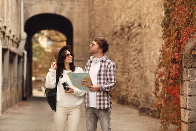 Photo of Couple of travelers with map and camera on city street