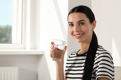 Photo of Young woman with glass of water indoors, space for text. Refreshing drink