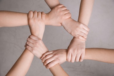 People holding hands together on grey background, top view. Responsibility concept