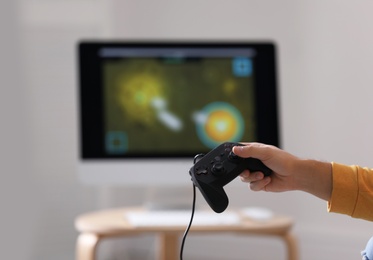 Young man holding video game controller against blurred background, closeup