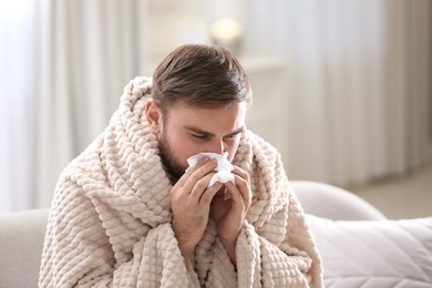 Young man suffering from runny nose in living room