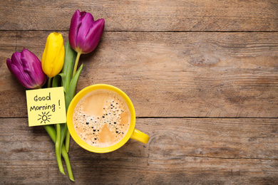 Delicious coffee, flowers and card with GOOD MORNING wish on wooden table, flat lay. Space for text