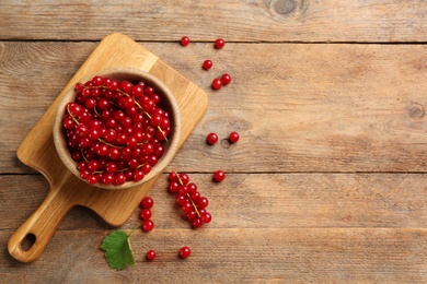 Delicious red currants on wooden table, flat lay. Space for text