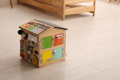 Busy board house on floor indoors, space for text. Baby sensory toy
