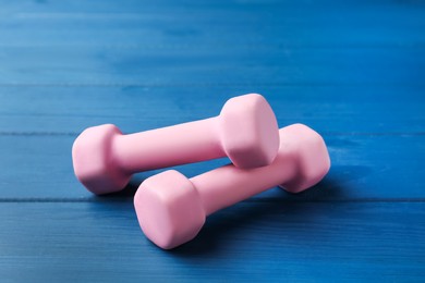 Pink rubber coated dumbbells on blue wooden table