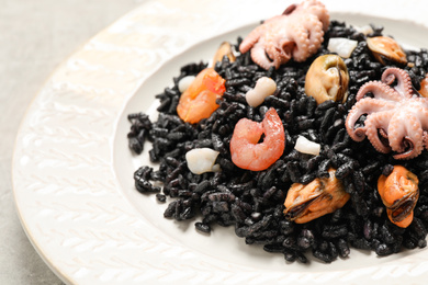 Delicious black risotto with seafood served on plate, closeup