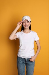 Young happy woman in white cap and tshirt on yellow background. Mockup for design