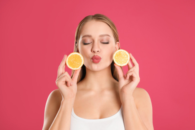 Photo of Young woman with cut lemon on pink background. Vitamin rich food