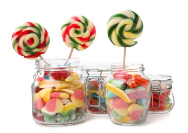 Jars with tasty jelly candies and lollipops on white background