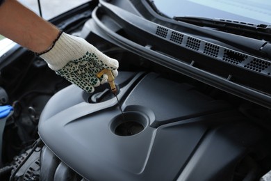Man checking motor oil level with dipstick in car engine, closeup