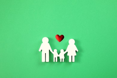 Family figure and red heart on green background, flat lay