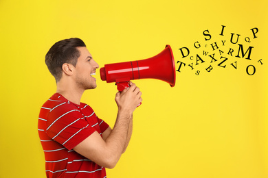 Handsome man with megaphone and letters on yellow background. Speech therapy concept