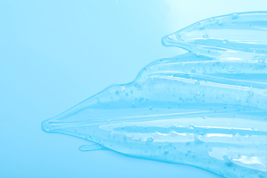 Pure transparent cosmetic gel on light blue background, top view