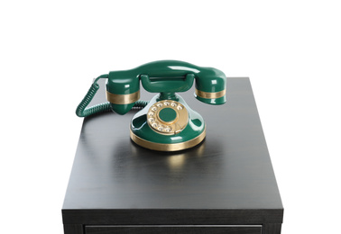 Green vintage corded phone on small black table against white background