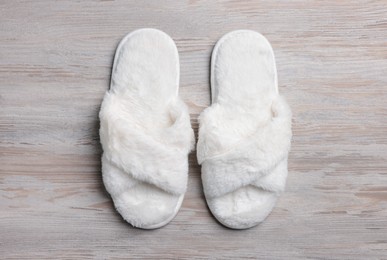 Pair of soft slippers on white wooden floor, top view
