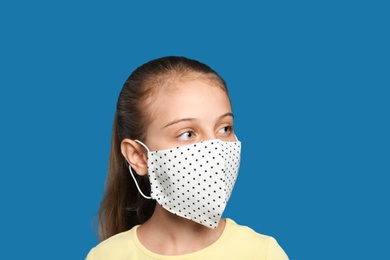 Photo of Preteen girl in protective face mask on blue background