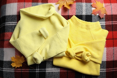 Beautiful yellow warm sweater and leaves on checkered plaid, flat lay