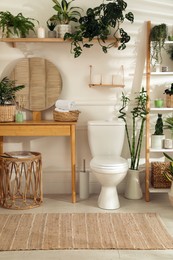 Stylish bathroom interior with toilet bowl and many beautiful houseplants