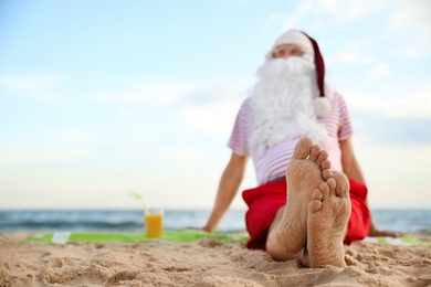 Santa Claus with cocktail relaxing on beach, space for text. Christmas vacation