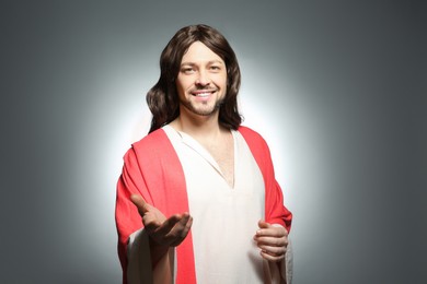 Jesus Christ reaching out his hand on grey background
