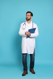 Full length portrait of doctor with stethoscope and clipboard on light blue background