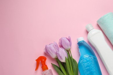 Photo of Spring cleaning. Detergents, flowers and rag on pink background, flat lay. Space for text