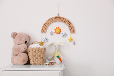 Commode with toys and diapers near light wall in baby room. Interior design