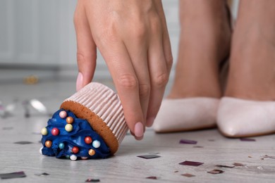 Woman picking up dropped cupcake from floor, closeup. Troubles happen
