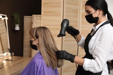 Professional stylist working with client in beauty salon. Hairdressing services during Coronavirus quarantine