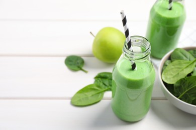Tasty fresh green smoothie near ingredients on white wooden table, space for text