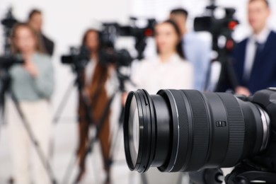 Photo of Professional video camera and group of journalists on background, closeup