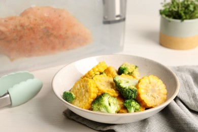 Photo of Bowl with delicious corn and broccoli on white wooden table. Sous vide cooking