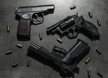 Different guns and bullets on grey table, flat lay