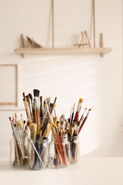 Different paintbrushes on white table indoors. Artist's workplace