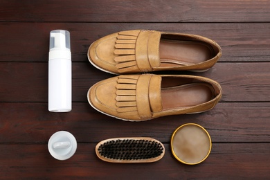 Flat lay composition with shoe care accessories and footwear on brown wooden background