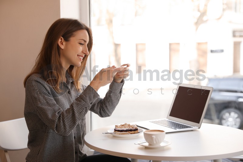 Young blogger taking photo of dessert in cafe
