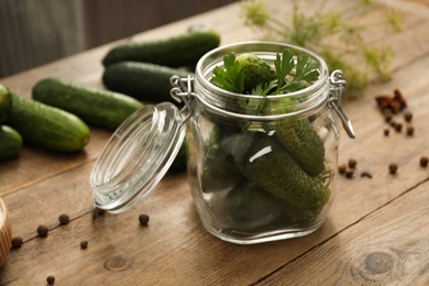 Pickling jar with fresh cucumbers on wooden kitchen table, closeup