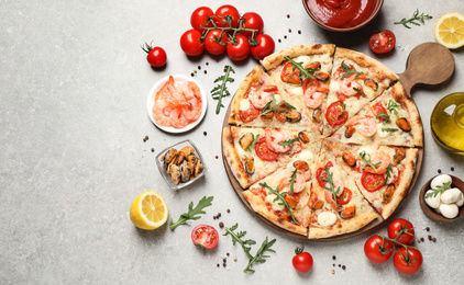Delicious seafood pizza and fresh ingredients on light grey table, flat lay