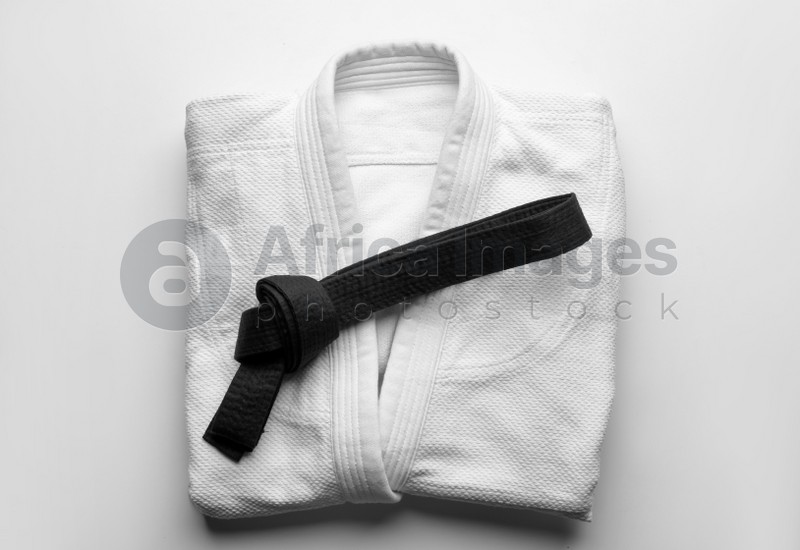 Photo of Martial arts uniform with black belt on white background, top view