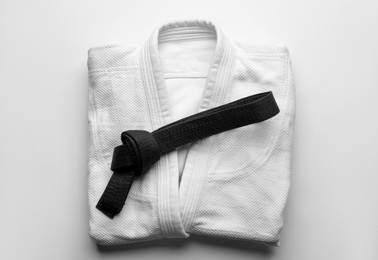 Martial arts uniform with black belt on white background, top view