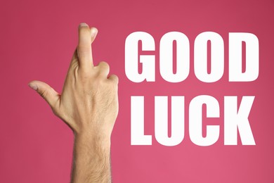 Man with crossed fingers on pink background, closeup. Good luck superstition