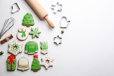 Kitchen utensils near Christmas tree shape made of delicious gingerbread cookies on white background, flat lay. Space for text