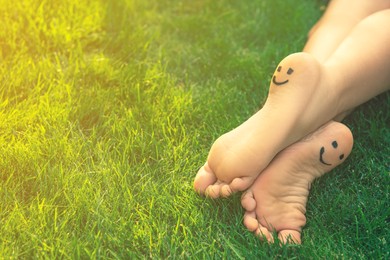 Teenage girl with smiling faces drawn on heels outdoors, closeup. Space for text